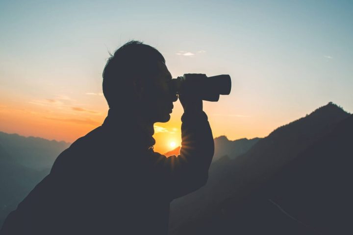 Silhouette of man looking through binoculars